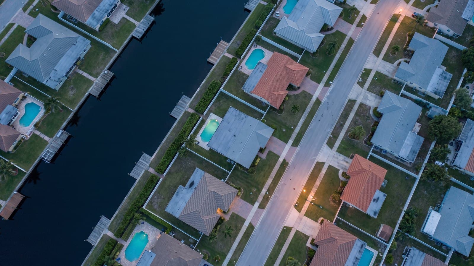 Aerial view at dusk of canal-front house lots and docks: the parcel grid an asset investigation reads in the land records