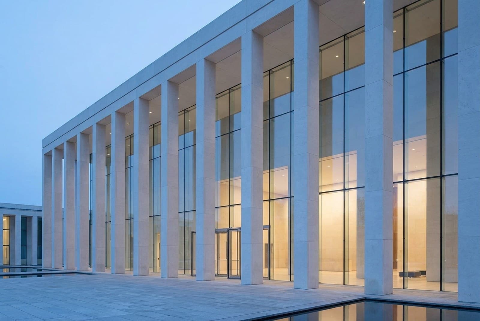 A modern courthouse colonnade in clean stone and glass at dusk, symbolising trial-bound litigation support work