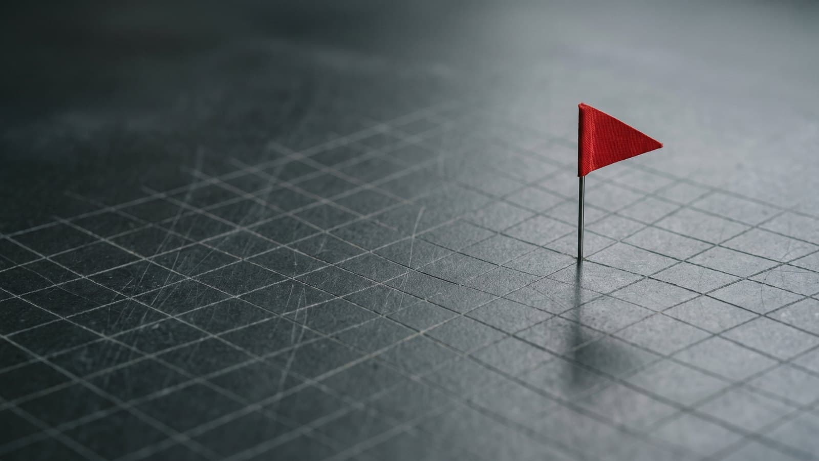 One small red flag pinned on a dark grid of blank squares: how red flags in due diligence surface among ordinary records
